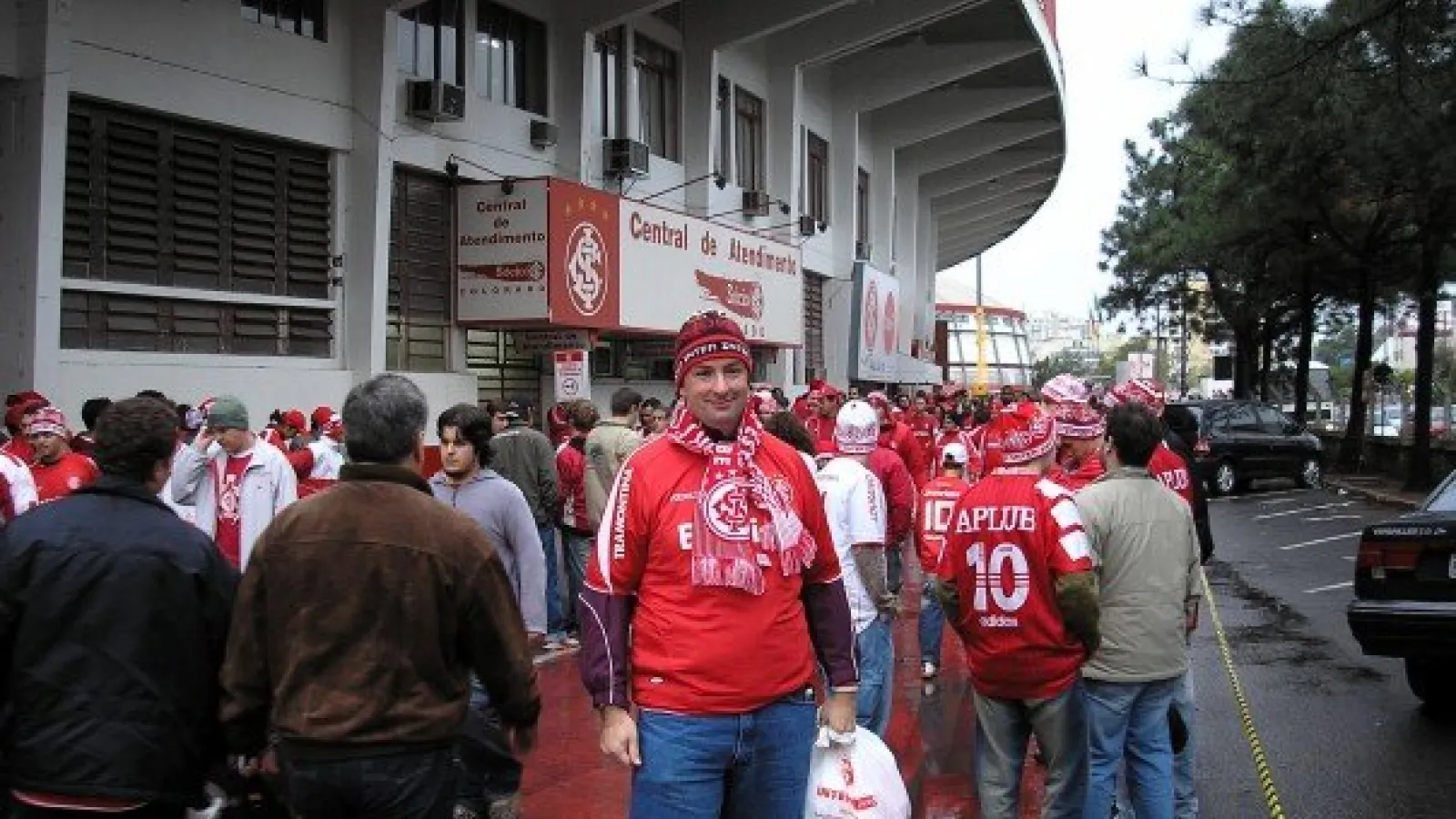 man in red in front of soccer stadium