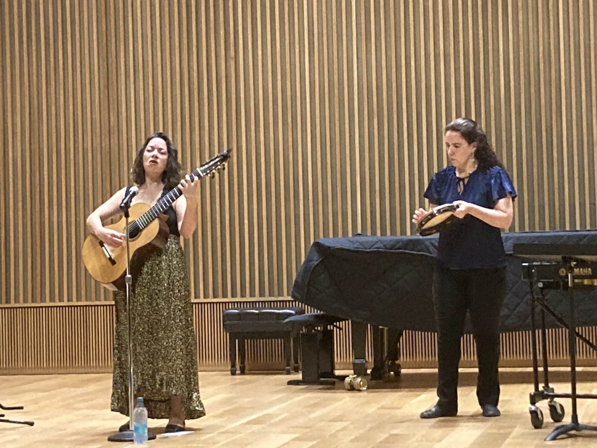 Percussionist Ana Leticia Barros plays the tamborine while Argentinian perfomer Cecilia Zabala sings and plays guitar during a recital