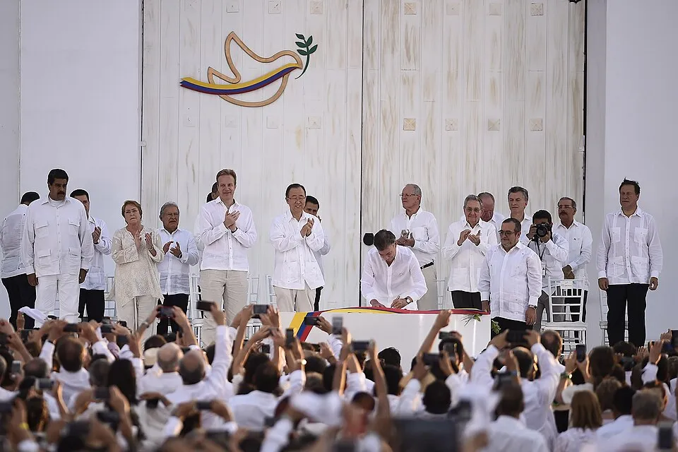 people wearing white on stage signing document